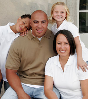 mother and father with two children sitting on a wall